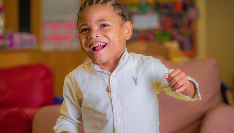 A young boy in a white shirt is smiling and laughing