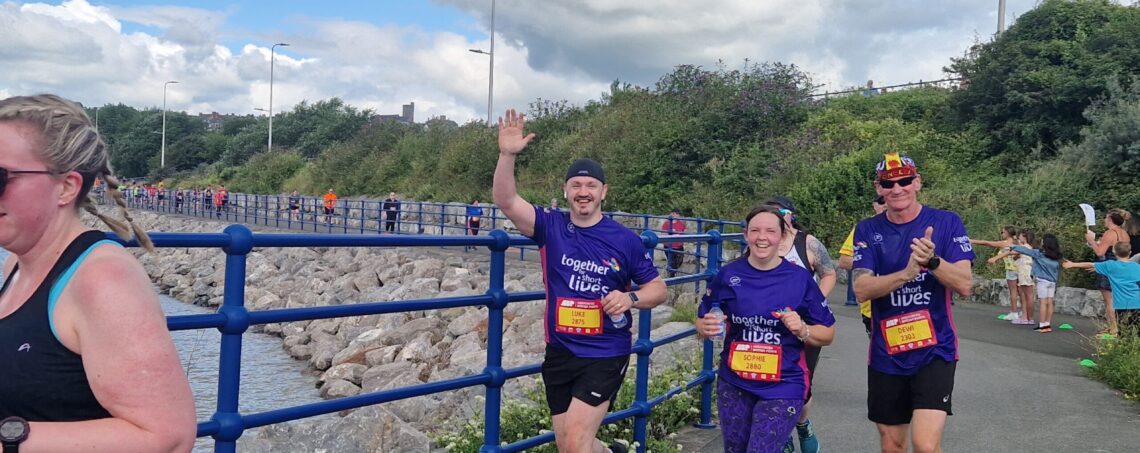 three runners smiling at camera as they race for Together for Short Lives