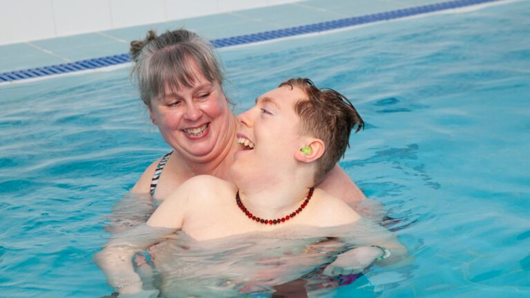 A mum and her son are hugging each other in a hydrotherapy pool