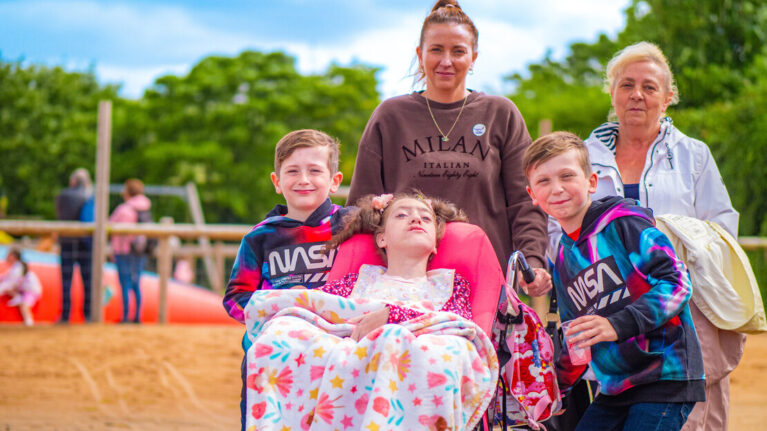 A family of five. Gemma, Gemma's mum, Teddie and Jesse gather around Olivia in her wheelchair.