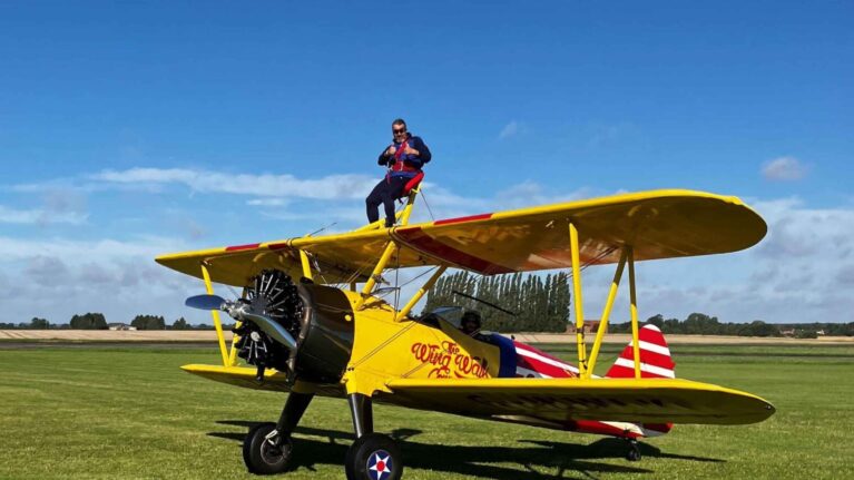 A man stands on top of a yellow plane