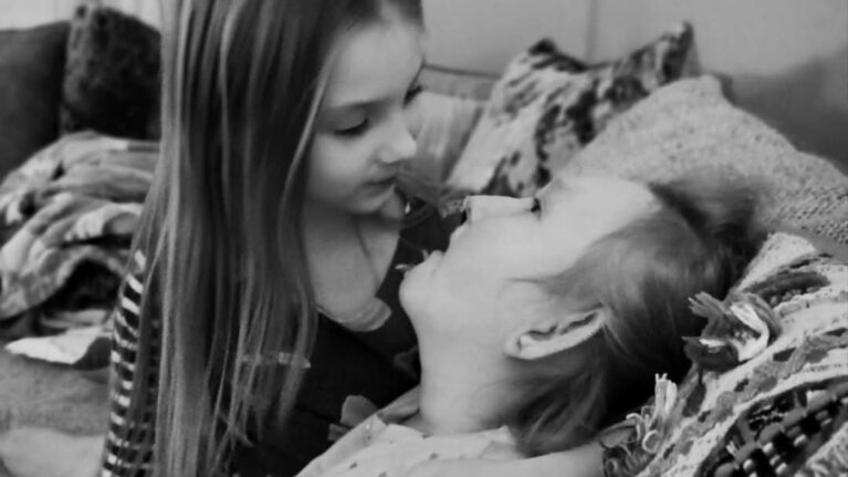Two young sisters gaze into each others eyes.