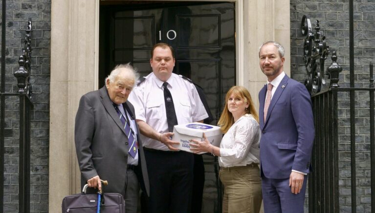 A group of four people are stood in front of Number 10 Downing Street.